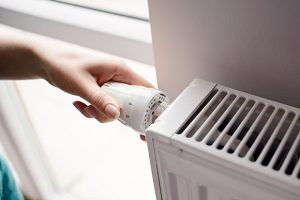 main sur une vanne thermostatique d'un radiateur