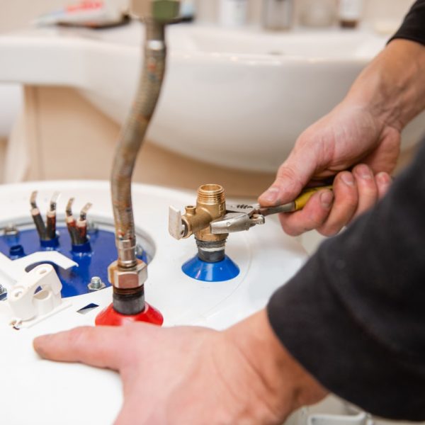 Home bathroom water heater fixing by hands close up